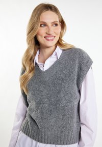 Grauer Strickpullover-Weste mit V-Ausschnitt und kurzen Ärmeln, mit einem gerippten Saum. Trägt man über einem weißen Hemd mit Kragen. Weiche Textur.