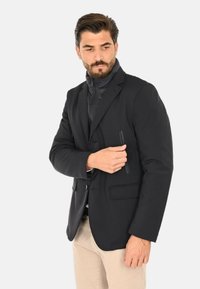 Blazer nero realizzato in tessuto liscio, caratterizzato da una vestibilità slim, rever con asola e una tasca sul petto con cerniera per una maggiore funzionalità.