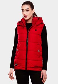 Gilet matelassé rouge avec capuche, fermeture éclair, texture matelassée, poches à boutons pression et logo noir sur la poitrine. Porté sur un pull noir.