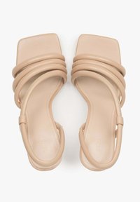 Beige vierkante sandalen met drie gebogen banden. Gladde textuur, minimalistisch ontwerp, open achterkant en platte zool.