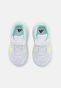 Baskets de sport blanches avec un dessus en mesh, présentant des accents pastel en vert menthe, rose et jaune fluo. Bande Velcro et détails de lacets.