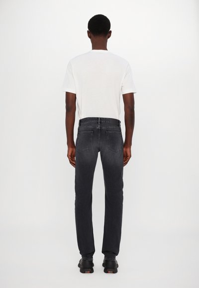 Jeans de mezclilla negros con un corte estándar, que cuentan con bolsillos traseros y una cintura de altura media, combinados con una camiseta blanca lisa.