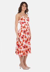 Abito midi floreale con spalline sottili, caratterizzato da uno sfondo bianco e grandi motivi floreali rossi e neri. Tessuto fluente con vita aderente.