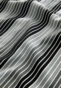 Schwarz-weiß gestreifter Stoff mit wellenförmigen Mustern und unterschiedlichen Texturen. Das Design umfasst dünne und dicke Linien, die Kontrast erzeugen.