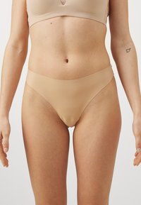 Bikini o kolorze nude, bezszwowy, z niskim stanem i gładką fakturą, zaprojektowany dla wygody i minimalnej widoczności pod odzieżą.