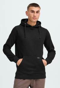 Sudadera negra de tela suave, con bolsillo canguro, cordones ajustables y puños acanalados. Diseño minimalista con detalle del logo.