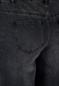 Mustad denim teksad, millel on sile tekstuur ja standardne lõige. Tunnustatud detailideks on tagakott kolmnurkse kujuga ja õmmeldud ääred.