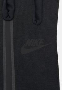 Fekete kötött kesztyű, amelyen egy kiemelkedő fekete Nike logó található, sima textúrával és letisztult, minimalista dizájnnal, finom szürke csíkokkal kiegészítve.