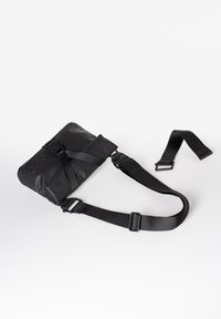 Black crossbody bag with adjustable nylon strap, rectangular shape, matte finish, featuring a zipper closure and branded detail.