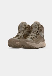 Botas de caminhada Lowa em caqui com um upper texturizado, apresentando fechos de atacador, colarinhos acolchoados e solas de borracha robustas para aderência.