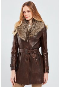 Brown leather coat with a wide faux fur collar, belted waist, two front pockets, and a structured, mid-length silhouette.