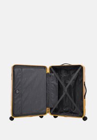 Žlutý tuhý kufr s černým vnitřkem, síťovanou kapsou a křížovými popruhy pro rozdělení prostoru. Čtyři kolečka pro snadnou manipulaci.