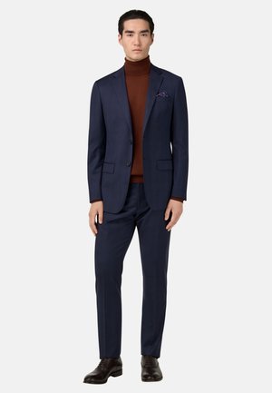 Costume marine avec un design texturé, associé à un col roulé marron. Comprend un pochette de costume et des chaussures en cuir marron brillantes. Ajustement sur mesure.