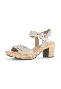 Beige suède sandalen met hakken, een verstelbare enkelband, een grote zilveren gesp en een gestructureerde kurken zool.