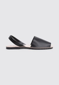 Sandal de piel negra de tiras con puntera cerrada, suela plana de goma y talón descubierto. Presenta una textura suave y un detalle de costura mínimo.