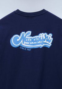 Μπλε ναυτικό βαμβακερό μπλουζάκι με μεγάλο λευκό και γαλάζιο λογότυπο "Napapijri" στην πλ άτη, με την ένδειξη "SINCE 1987" από κάτω.