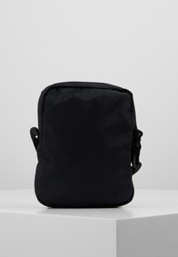 Sacchetto di stoffa nera di forma rettangolare, dotato di manico laterale e texture liscia, adatto per vari piccoli oggetti.