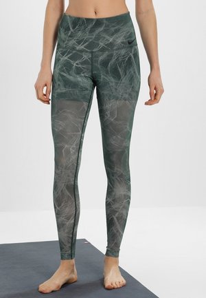 Leggings verts à motif avec une taille haute, fabriqués dans un tissu extensible et texturé. Présente un logo noir contrastant à la taille.