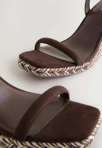 Sandali alti in suede marrone con doppie cinghie, punta quadrata e suola intrecciata con motivo a spina di pesce in marrone e crema.