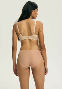 Biustonosz w kolorze cielistym oraz dopasowane wysokie majtki, wykonane z miękkiego materiału, z regulowanymi ramiączkami i zapięciem na haftki na biustonoszu.