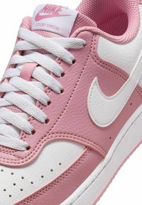 Sneakers Nike Court Vision in rosa e bianco, con materiali testurizzati, lacci bianchi, dettagli di cucitura e logo Nike swoosh bianco.