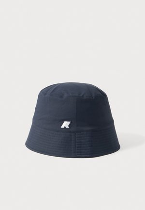 Marineblauwe bucket hat met een klein wit en zwart logo aan de voorkant, weergegeven op een effen lichtgrijze achtergrond.