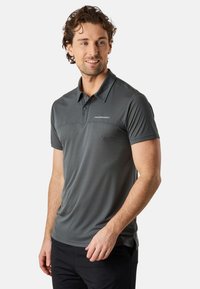 Grå pikétröja med strukturerad mönster, korta ärmar och en tvåknappsknäppning. Har en diskret logotyp på bröstet.