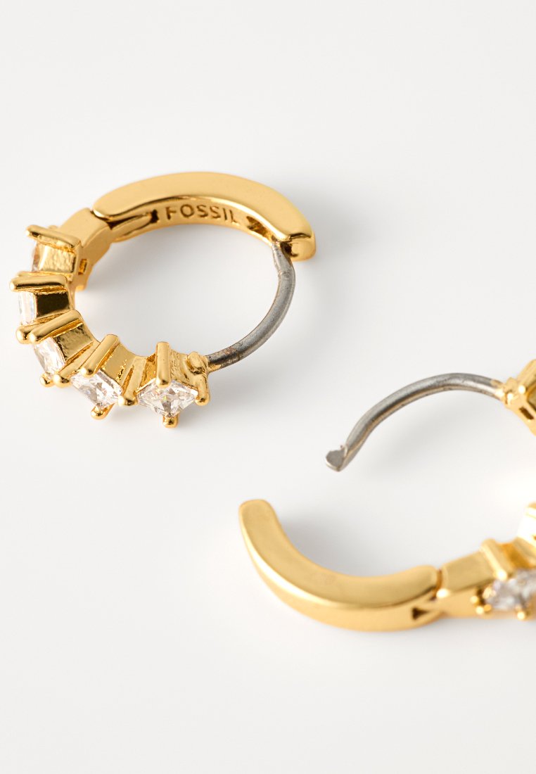 Boucles d'oreilles créoles dorées avec une rangée de pierres précieuses transparentes sur un côté, avec une texture lisse et un intérieur argenté contrastant.