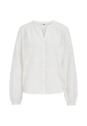 Blouse blanche à manches longues avec broderies florales, devant boutonné, encolure ronde, et poignets et épaules légèrement froncés.