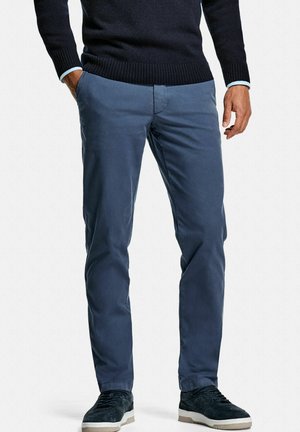 Marineblauwe chino's gemaakt van katoen met een gladde textuur, voorzien van een slim fit en zijzakken, gecombineerd met marineblauwe suède sneakers.