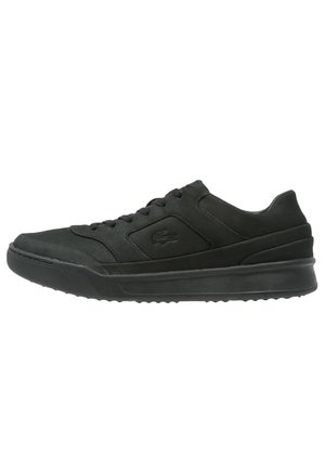 Czarne niskie sneakersy ze sznurowaniem z przodu, markowym logo krokodyla po bokach oraz grubą gumową podeszwą do codziennego użytku.