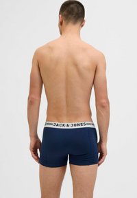 Tumši zili bokseršorti ar baltu jostu, uz kuras ir uzraksts "JACK & JONES". Audums izskatās gluds un elastīgs, pieguļot ķermenim.