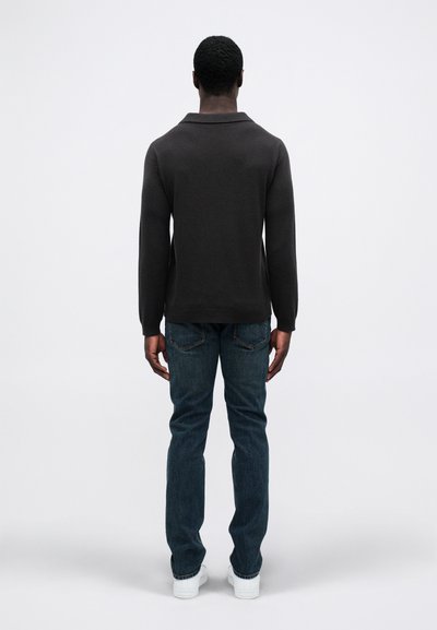 Ciemnoszara pulower z kołnierzykiem, dopasowany krój, długie rękawy; zestawiony z niebieskimi dżinsami i białymi trampkami, widok z tyłu.
