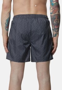 Boxer in nero con un motivo testuale ripetuto in bianco. Fascia elastica in vita, design morbido e tessuto liscia.