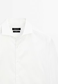 Weißes Hemd mit klassischem Kragen, strukturiertem Stoff, knöpfbarem Frontverschluss und einem Etikett, auf dem "Massimo Dutti" steht.