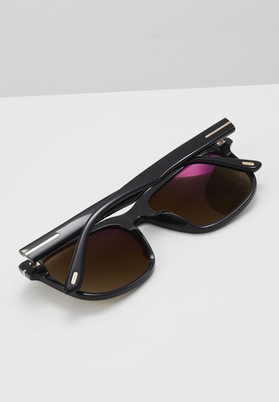 Black sunglasses with gradient brown lenses, a bold square shape, and glossy finish. Gold accents on the frames enhance the design.