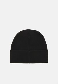 Fekete beanie sapka puha, rugalmas anyagból. Az alján hajtott mandzsettával és lekerekített tetejével rendelkezik. Egyszerű, egyszínű dizájn.