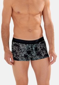 Schwarze Boxer mit floralem Muster in Dunkelgrün, ausgestattet mit einem schwarzen elastischen Bund mit Logo-Detail. Glatte Textur.