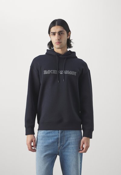 Felpa con cappuccio navy e cordino, con logo "EMPORIO ARMANI" in colore a contrasto. Tessuto morbido e liscio, polsini e orlo a costine.