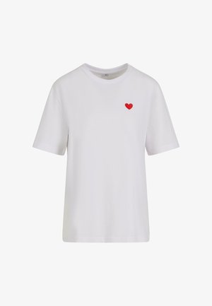 Valge puuvillane t-särk, millel on lühikesed varrukad, ümar kaelus ja väike punane tikand südame kujul vasakul rinnal.