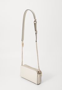 Crossbody torba u off-white imitaciji kože, pravokutnog oblika, s dva zatvorena pretinca, podesivim remenom s lancem, minimalističkog dizajna.