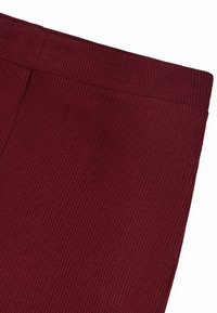 Bordeaux ribbelstof met een gladde, elastische textuur en een naadloze tailleband. De stof vertoont verticale lijnen.