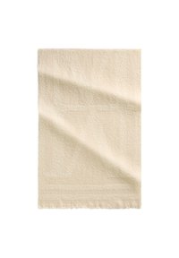 Roomkleurige rechthoekige handdoek met subtiele textuur en franjes aan de randen, plat liggend met zachte plooien op een witte achtergrond.