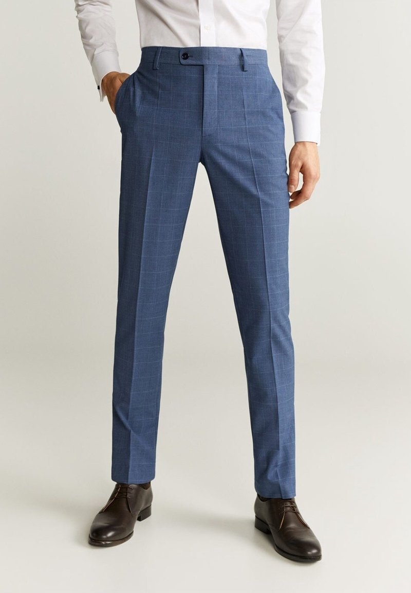 Pantalon de costume à carreaux slim-fit bleu pour homme, associé à des chaussures en cuir marron à lacets et une chemise blanche.