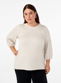 Pullover beige con maniche a tre quarti, scollatura rotonda e dettagli floreali ricamati sulle spalle. Tessuto morbido e vestibilità comoda.