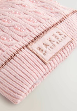 Un textile tricoté rose avec un motif de câble en relief, orné de perles roses, finition bord côtelé et une étiquette rectangulaire portant la mention "BAKER."