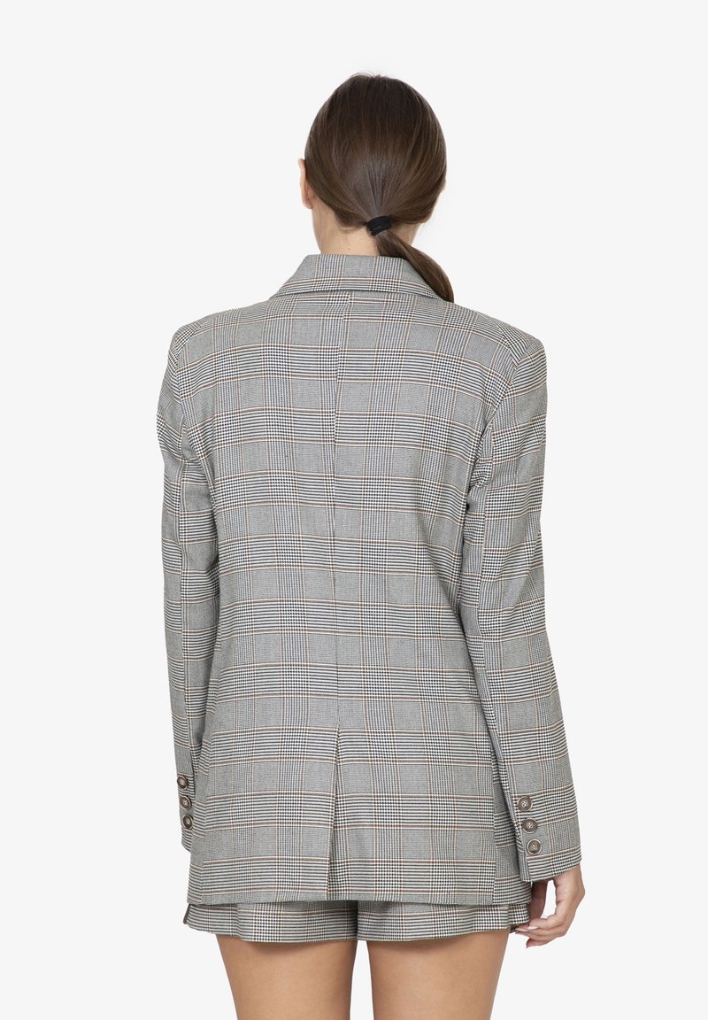 Grijze geruite blazer met een gestructureerd ontwerp, dubbele ventilatie aan de achterkant en manchetknopen met vier knopen. De stof vertoont een ruitpatroon met subtiele bruine accenten.