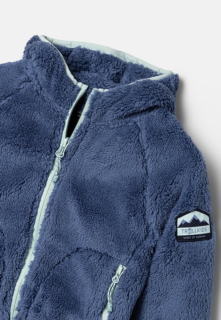 Dunkelblaues Fleece-Jacke mit Kapuze, ausgestattet mit einem durchgehenden Reißverschluss, strukturiertem Oberflächenmaterial und einem Aufnäher mit Bergdesign am linken Ärmel.