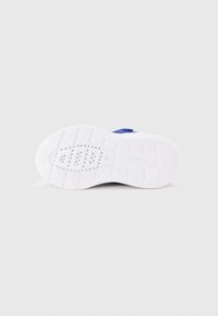 Λευκή σόλα αθλητικού παπουτσιού με υφή σχεδίου, που διαθέτει αυλακώσεις για πρόσφυση και ένα μικρό λογότυπο της μάρκας ανάγλυφο στο πλάι.