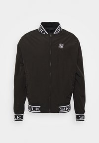 Černá zipová bunda s bílým logem "SIKSILK" na límci, manžetách a lemu, s malým bílým logem na hrudi.